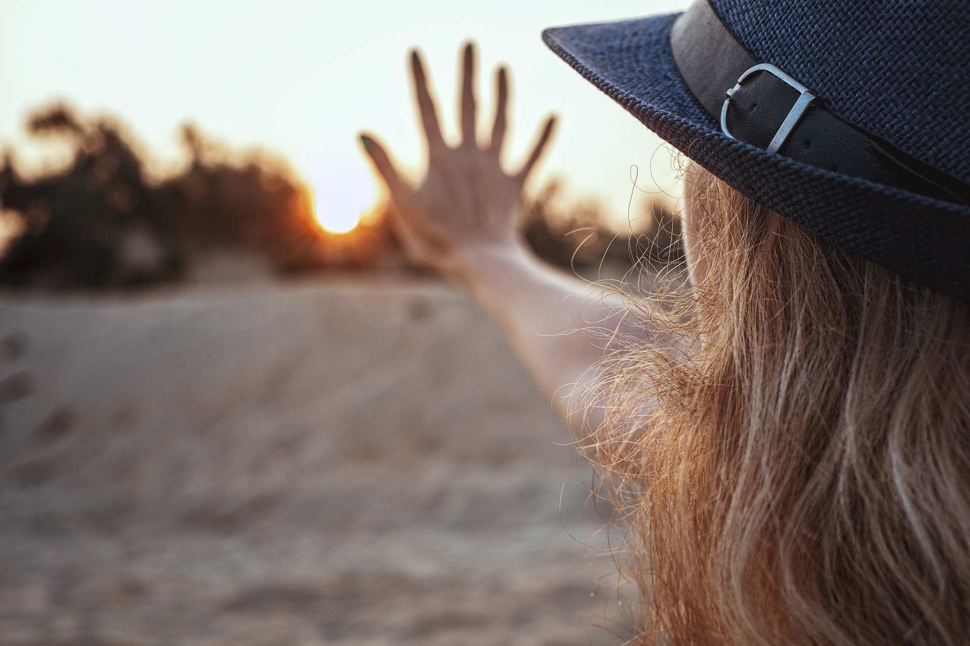 Karma - was ist das eigentlich? Frau mit Hut und Hand vor Sonnenaufgang